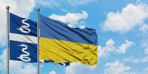 Martinique and Ukraine flag waving in the wind against white cloudy blue sky together. Diplomacy concept, international relations.