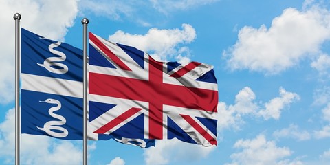 Martinique and United Kingdom flag waving in the wind against white cloudy blue sky together. Diplomacy concept, international relations.