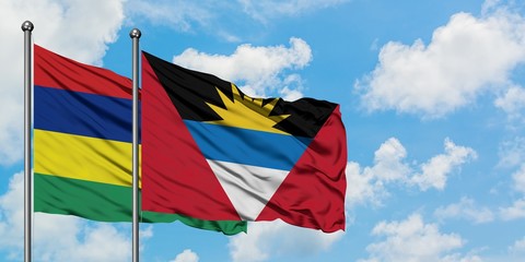 Mauritius and Antigua and Barbuda flag waving in the wind against white cloudy blue sky together. Diplomacy concept, international relations.
