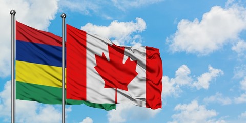 Mauritius and Canada flag waving in the wind against white cloudy blue sky together. Diplomacy concept, international relations.