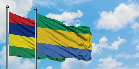 Mauritius and Gabon flag waving in the wind against white cloudy blue sky together. Diplomacy...