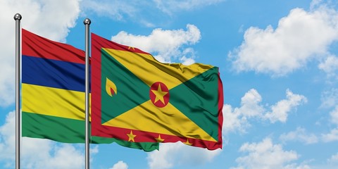 Mauritius and Grenada flag waving in the wind against white cloudy blue sky together. Diplomacy concept, international relations.