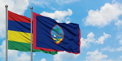 Mauritius and Guam flag waving in the wind against white cloudy blue sky together. Diplomacy concept, international relations.