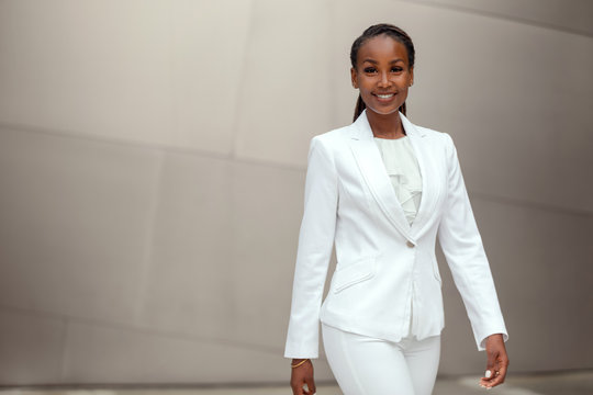 Sharply dressed stylish business woman walking portrait in suit at office financial workplace. african american female
