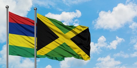 Mauritius and Jamaica flag waving in the wind against white cloudy blue sky together. Diplomacy concept, international relations.