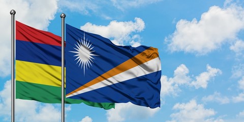 Mauritius and Marshall Islands flag waving in the wind against white cloudy blue sky together....