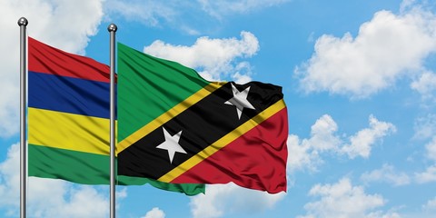 Mauritius and Saint Kitts And Nevis flag waving in the wind against white cloudy blue sky together. Diplomacy concept, international relations.