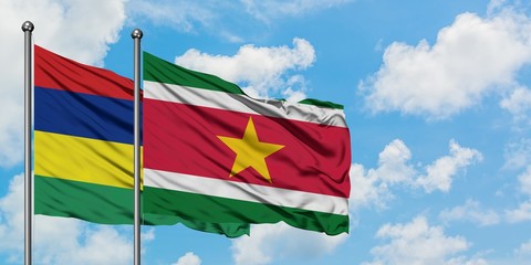 Mauritius and Suriname flag waving in the wind against white cloudy blue sky together. Diplomacy concept, international relations.