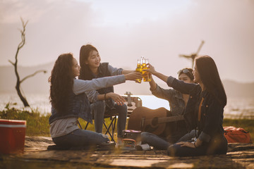 Group of happy friends while enjoying picnic a meal and drinks near amidst nature and water in a park, Cheerful Concept Friendship,image not focus, Camping and travel concept.