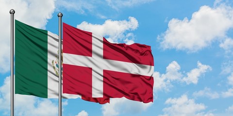 Mexico and Denmark flag waving in the wind against white cloudy blue sky together. Diplomacy concept, international relations.