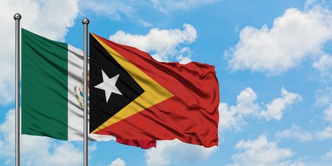 Mexico and East Timor flag waving in the wind against white cloudy blue sky together. Diplomacy concept, international relations.