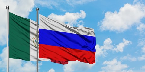 Mexico and Russia flag waving in the wind against white cloudy blue sky together. Diplomacy concept, international relations.
