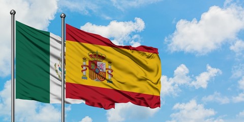 Mexico and Spain flag waving in the wind against white cloudy blue sky together. Diplomacy concept, international relations.