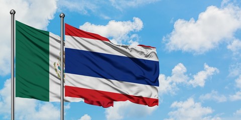 Mexico and Thailand flag waving in the wind against white cloudy blue sky together. Diplomacy concept, international relations.