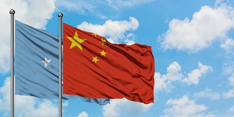 Micronesia and China flag waving in the wind against white cloudy blue sky together. Diplomacy concept, international relations.