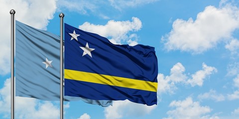 Micronesia and Curacao flag waving in the wind against white cloudy blue sky together. Diplomacy concept, international relations.