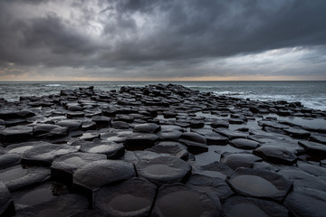 The natural hexagonal stones at the coast called Giant's Causeway, a landmark in Northern Ireland with dramatic cloudy sky.