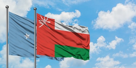 Micronesia and Oman flag waving in the wind against white cloudy blue sky together. Diplomacy concept, international relations.