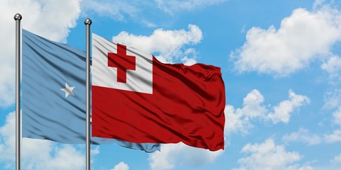 Micronesia and Tonga flag waving in the wind against white cloudy blue sky together. Diplomacy concept, international relations.