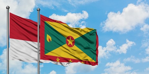 Monaco and Grenada flag waving in the wind against white cloudy blue sky together. Diplomacy concept, international relations.