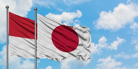 Monaco and Japan flag waving in the wind against white cloudy blue sky together. Diplomacy concept, international relations.