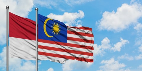 Monaco and Malaysia flag waving in the wind against white cloudy blue sky together. Diplomacy concept, international relations.