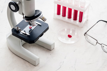 Blood testing laboratory. Samples viewing under microscope near tubes on white background top view copy space