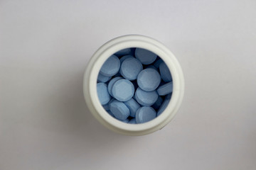 blue tablets in white plastic jar in medical healthcare drugstore concept,closed up