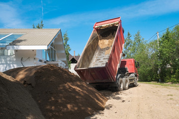 Fototapeta premium truck pours sand on the construction site