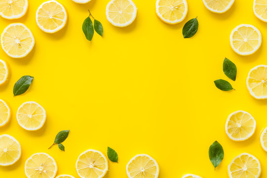 Fruit frame. Lemons and leaves on yellow background top view space for text