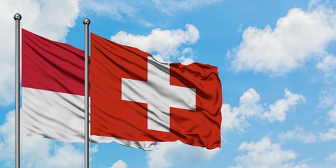 Monaco and Switzerland flag waving in the wind against white cloudy blue sky together. Diplomacy concept, international relations.
