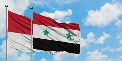 Monaco and Syria flag waving in the wind against white cloudy blue sky together. Diplomacy concept, international relations.