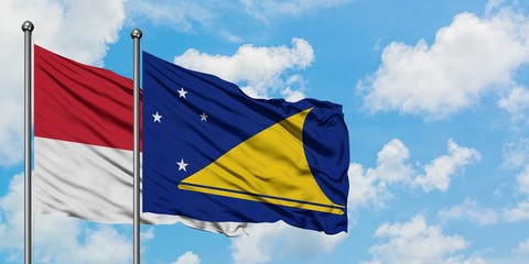 Monaco and Tokelau flag waving in the wind against white cloudy blue sky together. Diplomacy concept, international relations.