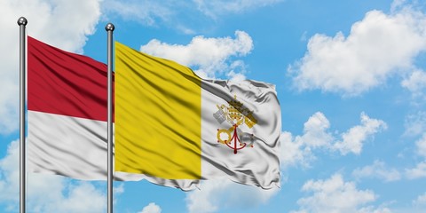 Monaco and Vatican City flag waving in the wind against white cloudy blue sky together. Diplomacy concept, international relations.