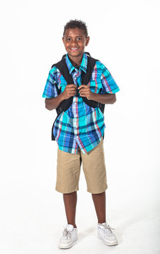 Smiling African American school boy isolated on white background. Wearing a backpack and a plaid shirt and ready to go to school. Front view