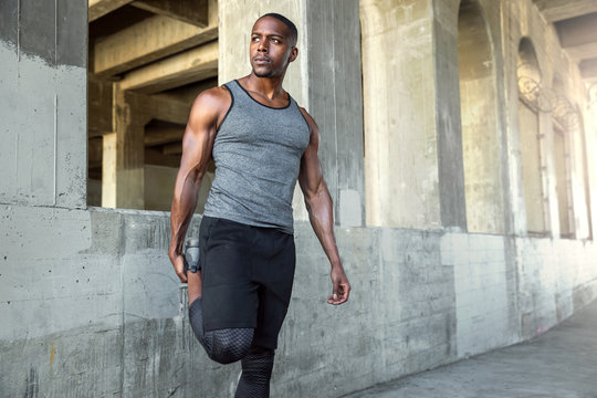 Strong Male Athlete In Sportswear Stretching Legs, Preparing For City Jog, Urban Fitness And Exercise