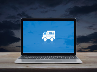 Free delivery truck flat icon with modern laptop computer on wooden table over sunset sky, Business transportation online concept