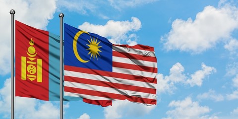 Mongolia and Malaysia flag waving in the wind against white cloudy blue sky together. Diplomacy concept, international relations.