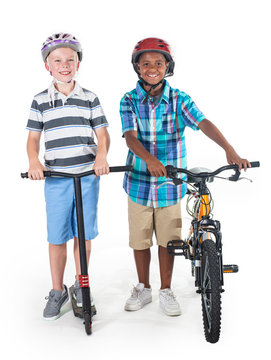 Two smiling diverse schoolboys isolated on a white background. Full length photo of the boys On their way to school riding a bike and a scooter. Education concept photo