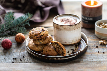 Homemade cookies with nuts and coffee in a ceramic cup on a wooden table with toys and Christmas tree branches