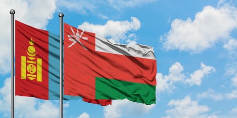 Mongolia and Oman flag waving in the wind against white cloudy blue sky together. Diplomacy concept, international relations.