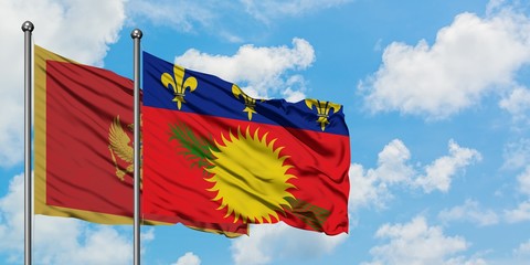 Montenegro and Guadeloupe flag waving in the wind against white cloudy blue sky together. Diplomacy concept, international relations.