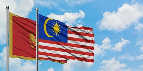 Montenegro and Malaysia flag waving in the wind against white cloudy blue sky together. Diplomacy concept, international relations.