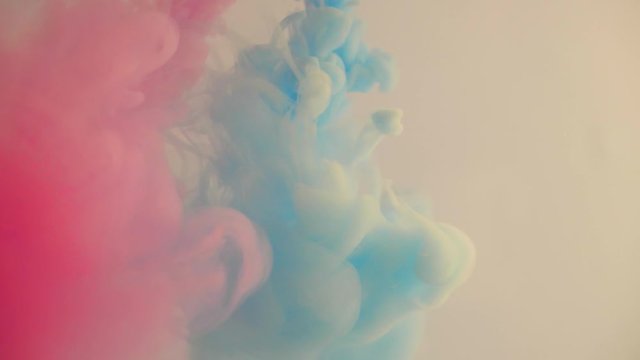 Pink and blue inks pour into the water. Diffusion of bright colors of paint. Colored paint slowly dissolves in water. Dilution of smoke in a liquid, a vivid mix that is pleasant to look at.