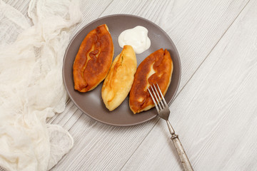 Plate with fried pies and fork on wooden boards
