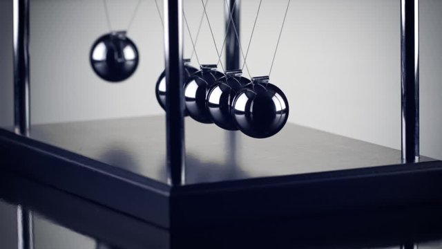 The chrome balls of a Newton&rsquo;s Cradle colliding in slow motion