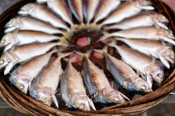 Steamed mackerel sold in the market. Mackerel fishes in round bamboo basket. Thai steamed mackerel fishes boiled cooking ready to eat in tray display for sale customer in market. Selected focus