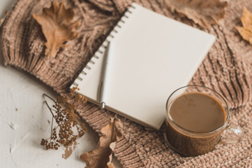 Background with notebook, pen, cup of coffee and sweater. Autumn planning with space for text.