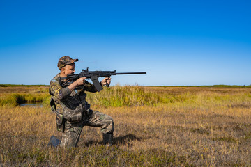 man with a gun standing in the field