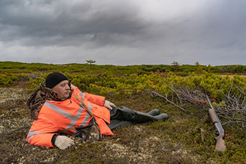 man with a gun resting in the field